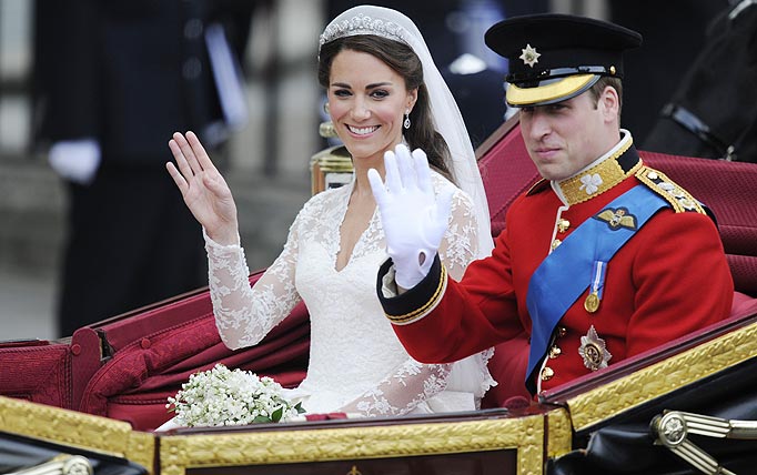 Britain's Prince William and his wife Kate, Duchess of Cambridge, wave as they travel in the 1902 State Landau carriage along the Processional Route to Buckingham Palace, in London, on April 29, 2011.