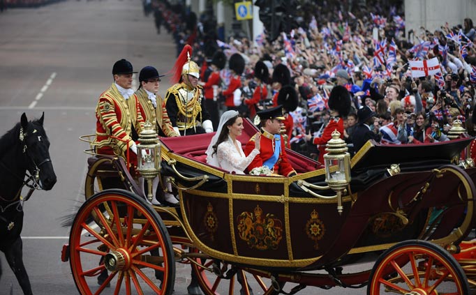 Britain's Prince William and his wife Kate, Duchess of Cambridge, wave as they travel in the 1902 State Landau carriage along the Processional Route to Buckingham Palace, after their wedding service, in London, on April 29, 2011.