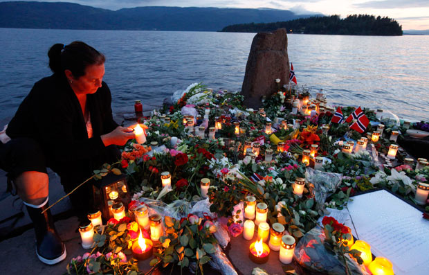 A woman lights a candle to pay her respects to the victims of the shooting spree and bomb attack in Norway, on the shore in front of Utoeya island, northwest of Oslo in this July 26, 2011