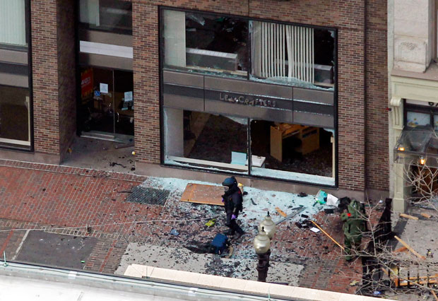 A man in a bomb-disposal suit investigates the site of an explosion