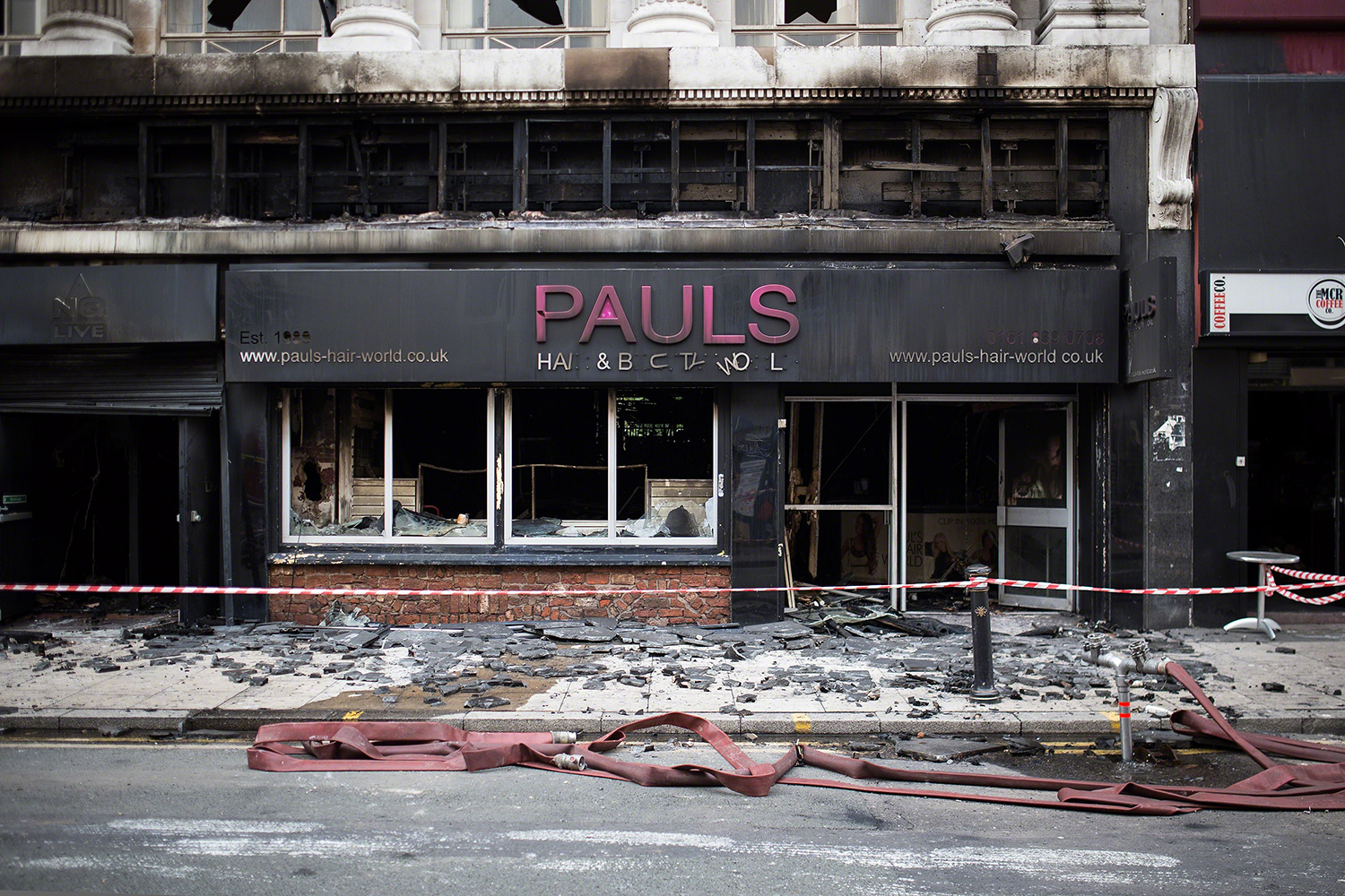 The scene on Oldham Street following a fire at Paul 's Hair World on 13th July which claimed the life of fireman Stephen Hunt .