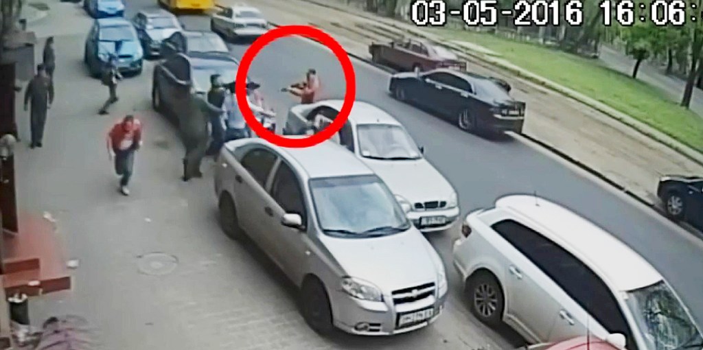  The thug is seen pulling a pump-action rifle out of the boot of the car and walking back across the road before opening fire on the journalists