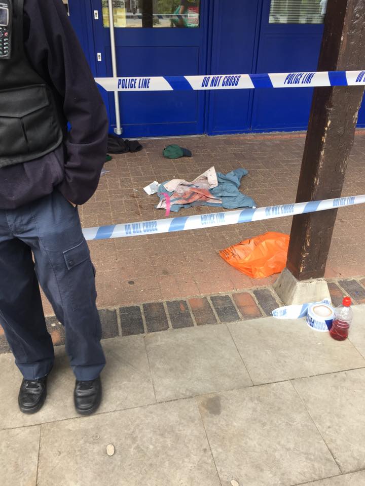  What appears to be a bloodied jacket can be seen lying on the ground next to a discard baseball cap