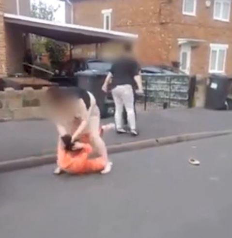  The woman in the tracksuit cowers under a torrent of kicks and punches while her attacker yells "I'll f***ing kill you"