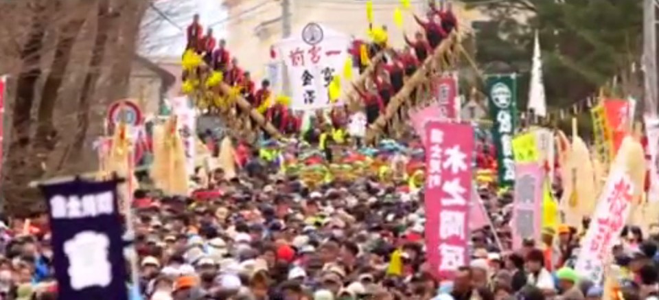  Massive crowds of people help to pull the huge logs to be blessed at the Shinto shrine