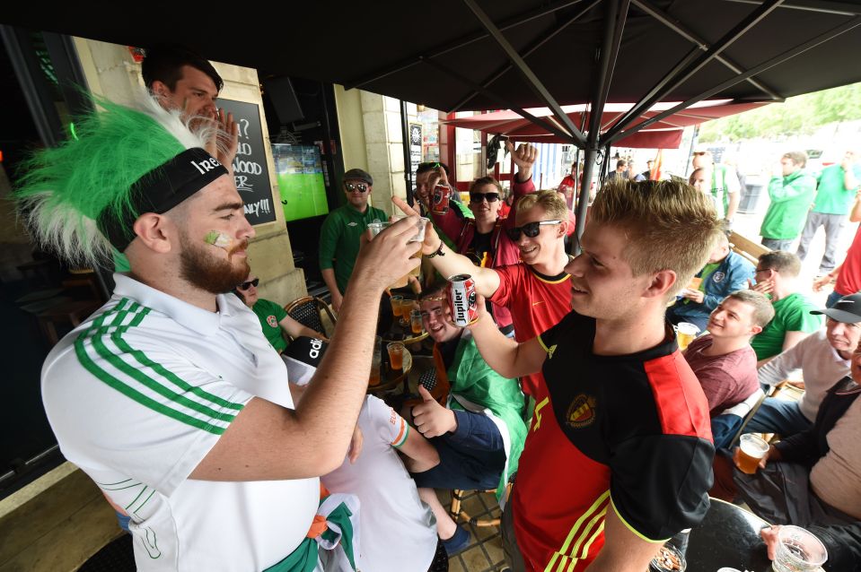 Belgium's supporters (R) and supporters of the Republic of Ireland (L) raise their drinks and toast as they watch the screening of the Euro 2016 group E football match between Italy and Sweden, on June 17, 2016 on a cafe terrace in Bordeaux. / AFP / Mehdi FEDOUACH (Photo credit should read MEHDI FEDOUACH/AFP/Getty Images)