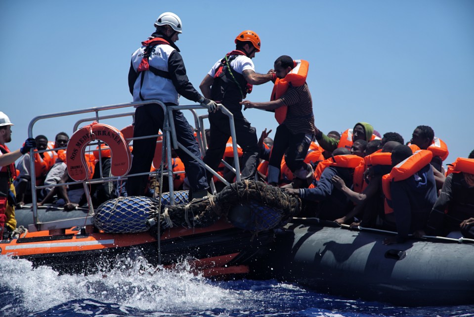  Rescue workers help migrants to disembark from a dinghy