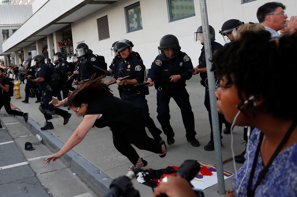  A woman falls off the pavement beside a police lineup