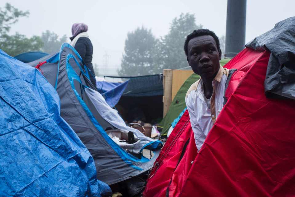 A migrant looks out of his tent just before being told to move on