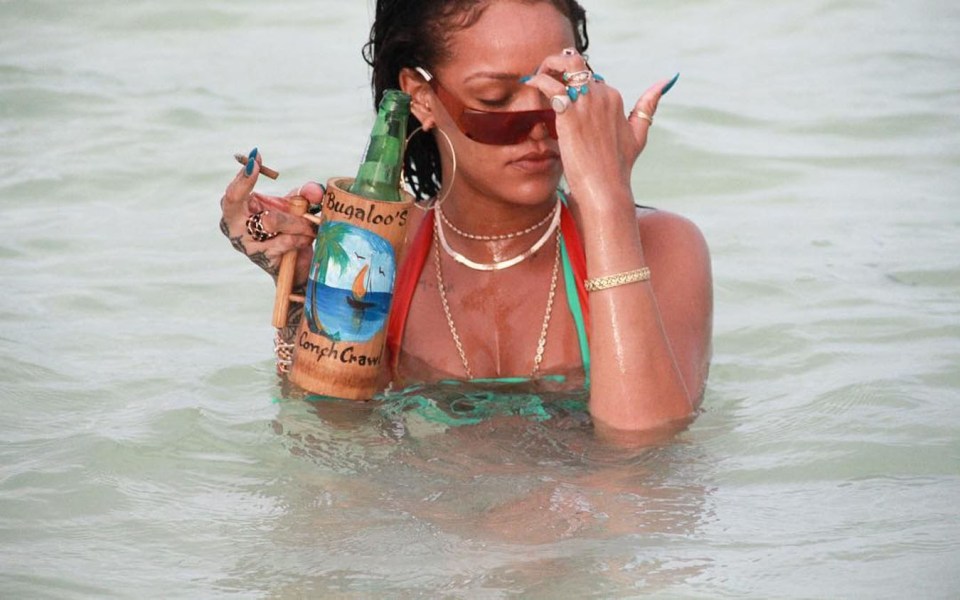 Rihanna heads into the water with a bottle of beer