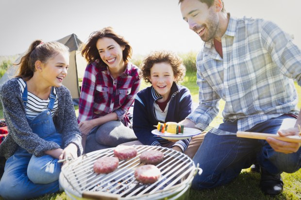 Family barbecuing at sunny campsite