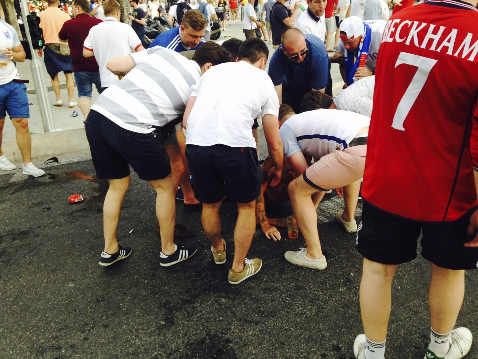  Three Lions supporters attend to an injured fan after clashes