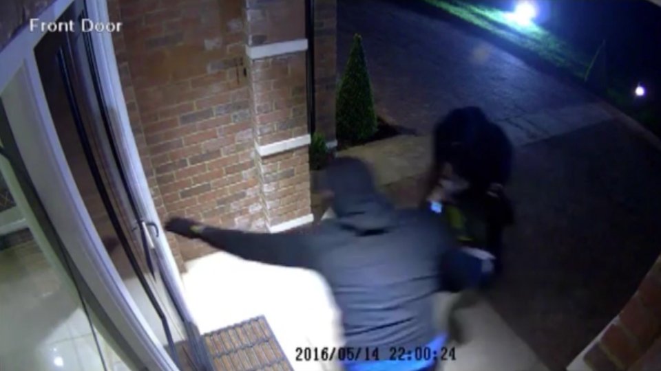 One of robbers wedges open the door before the pair bundle the woman through the front door