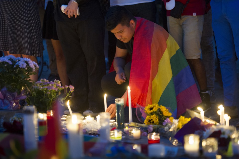  An man, wrapped in a Rainbow Flag, lights a candle during a vigil in Washington