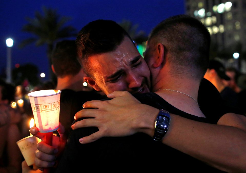  People embrace during a candlelight vigil at a memorial service for the victims of the shooting at the Pulse gay night club in Orlando