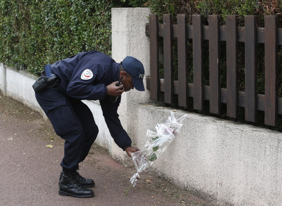 A French police officer lays flowers while paying tribute to his colleagues killed in a knife attack near their home