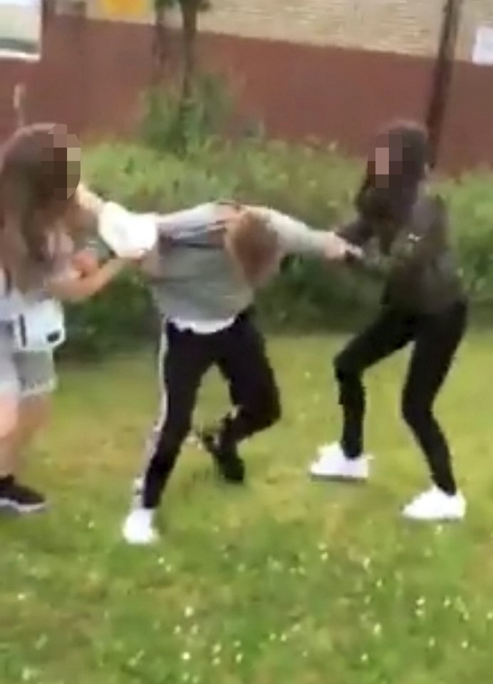 The bully girls use all their strength to restrain the young boy before kicking him violently