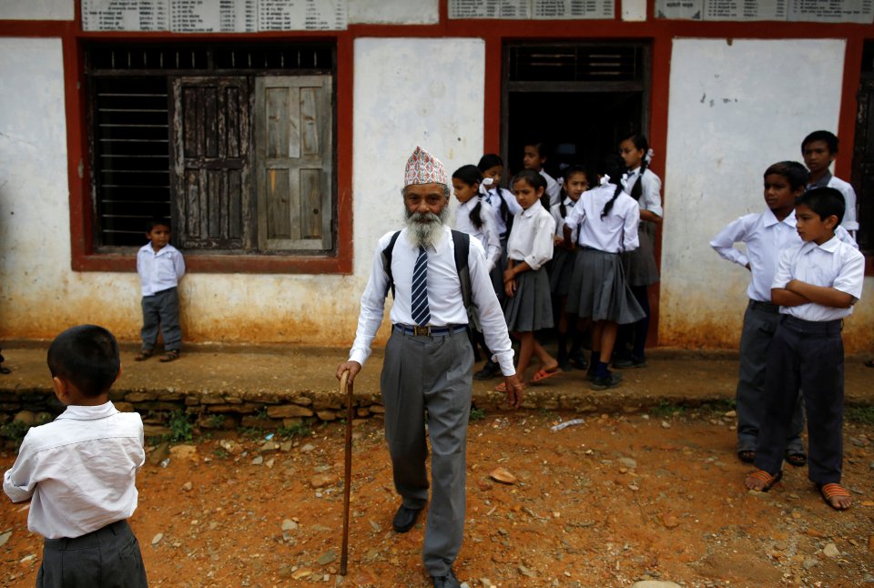 Dressed smartly in a white shirt and tie, 68-year-old Durga Kami walks an hour to and from school everyday with a walking stick to support him