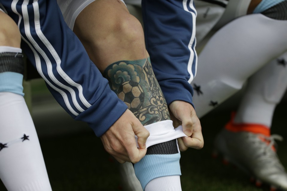 Lionel Messi shows off the tattoo on his left leg as he adjusts his socks