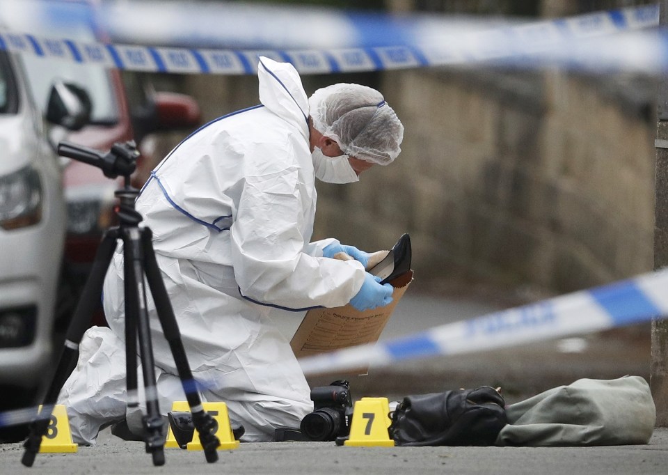  Forensics police officers collect a woman's shoes on the ground behind a police cordon in Birstall near Leeds