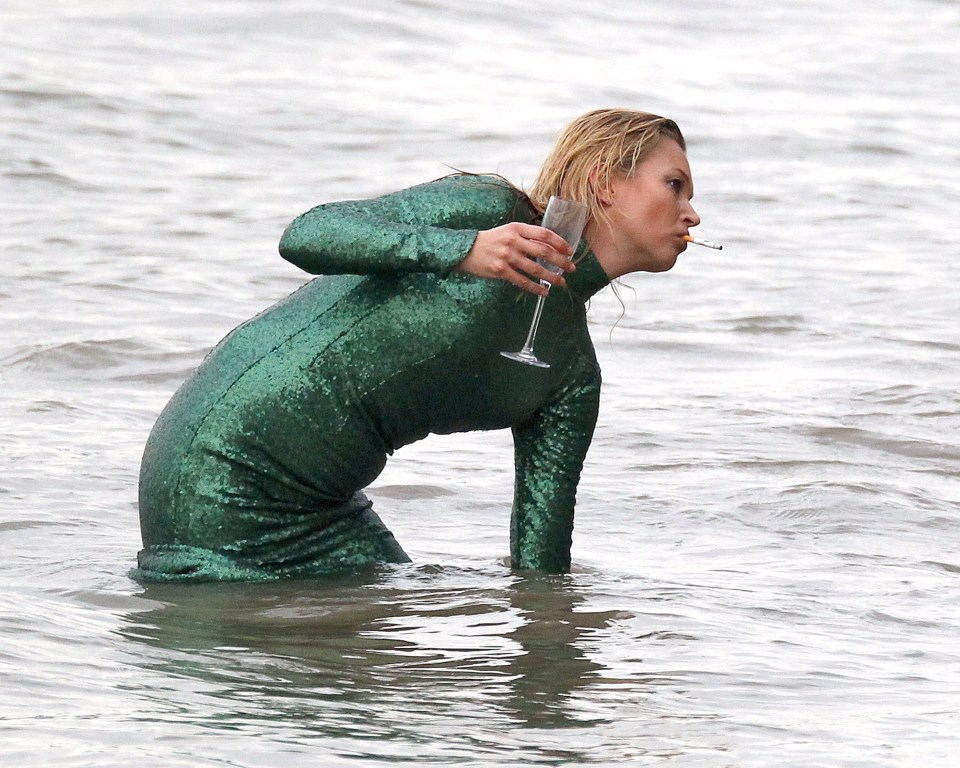  In the film she can be seen emerging from the sea puffing on a fag and clutching a glass of champagne