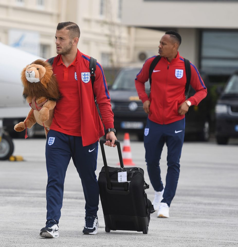 Jack Wilshere holds Leo the Lion as Nathaniel Clyne follows him off the plane