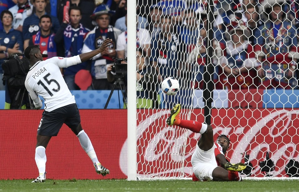  Switzerland's Johan Djourou, on the ground, goes for the ball with Paul Pogba