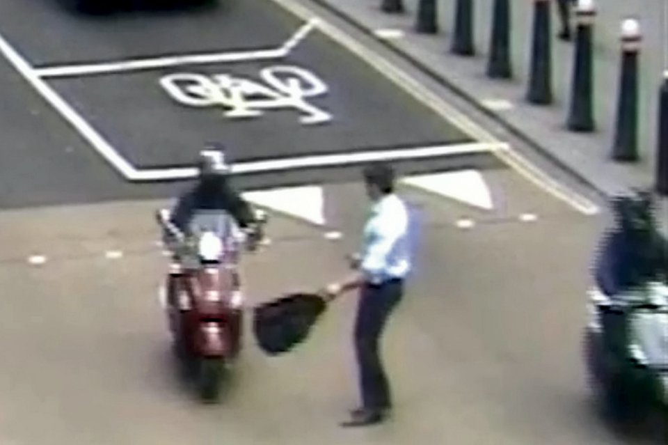 Surrounded by the mopeds, the man is left stunned as one reaches over to grab his phone