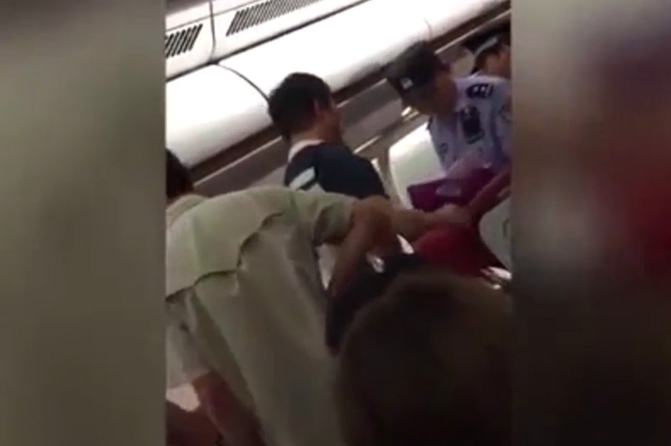  Passengers are seen taking suitcases from the overhead luggage racks