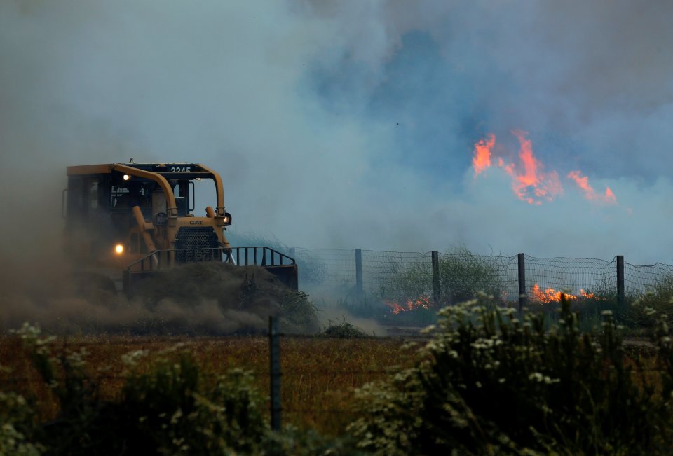 Firefighters battle a wildfire in temperatures well over 100F as it burns near Potero