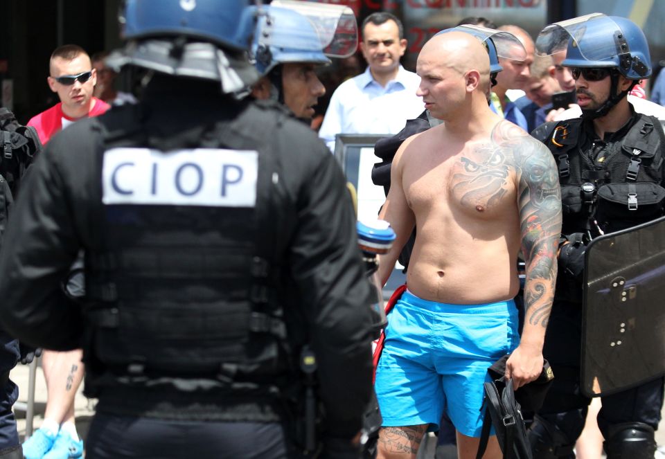  Riot cops speak to a man with colourful tatt down one arm as 'Ultras' clashed before Ukraine's game against Poland in Marseilles