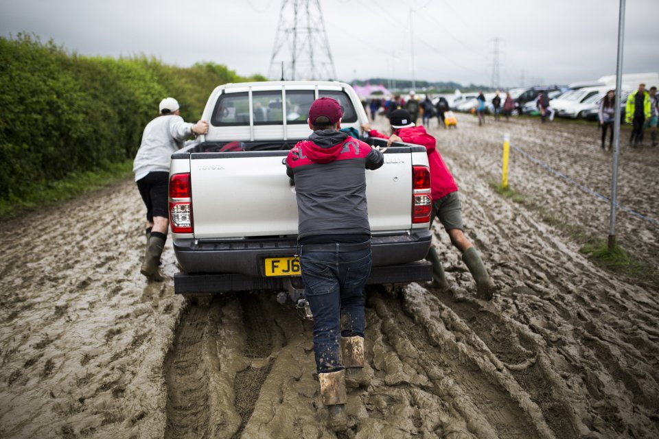  Three pals push a car through the quagmire at Glastonbury today