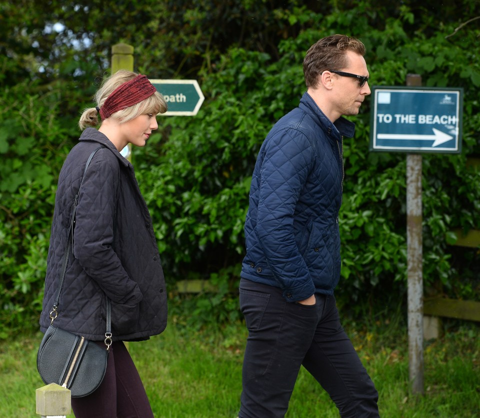  To the beach with you! The couple meander towards the water with Tom looking as serious as Loki under his Raybans