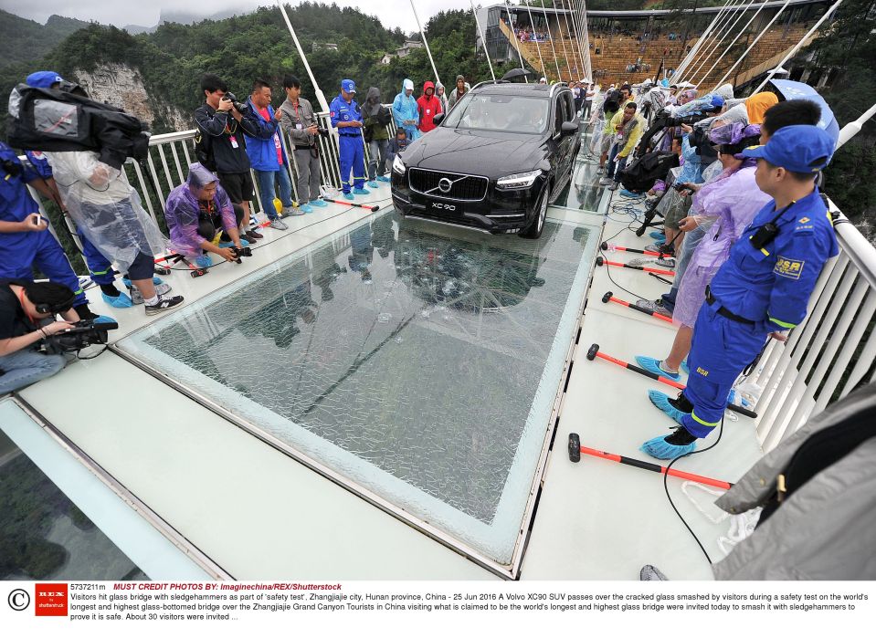 A car filled with passengers drives across a glass-bottomed suspension bridge in Zhangjiajie in southern China's Hunan province