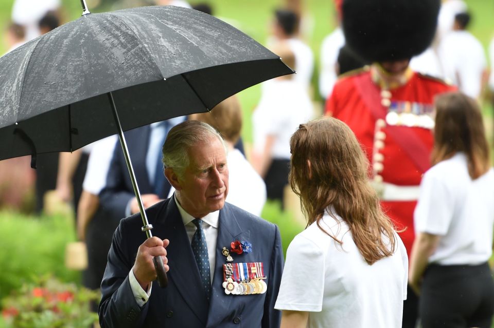  Prince Charles speaks to a young girl in the pouring rain