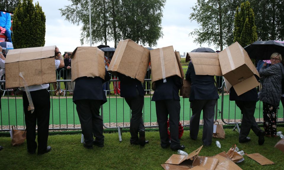  A group of people use cardboard boxes to shelter from the rain