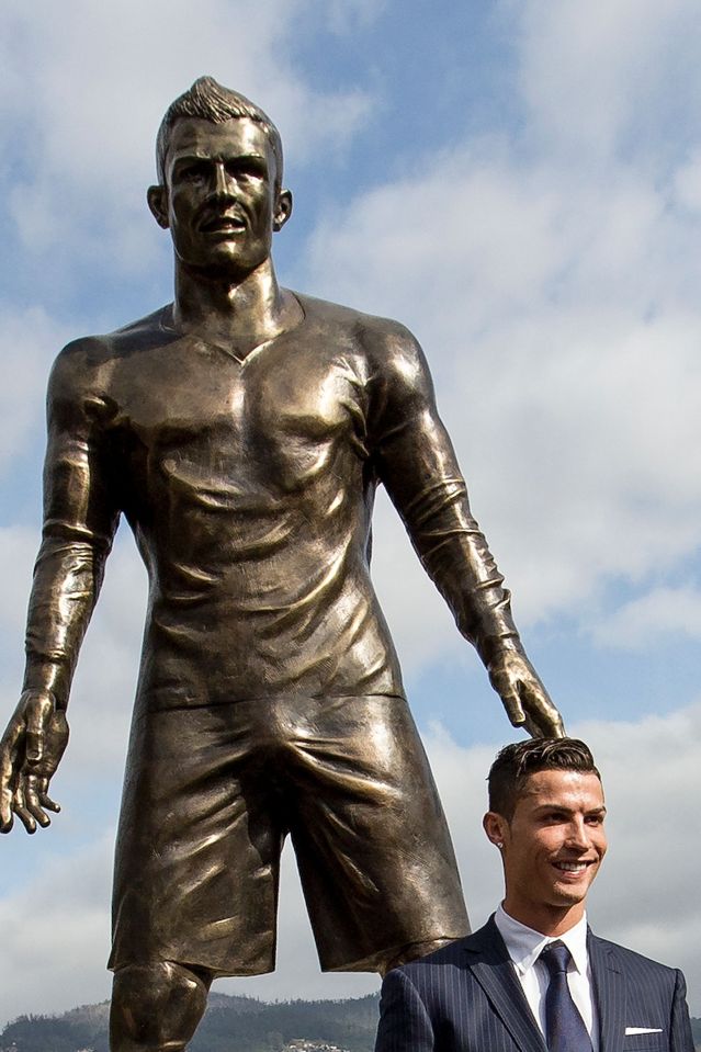 Cristiano Ronaldo from the Real Madrid poses beneath a statue of himself during the unveiling ceremony in his hometown of Funchal 