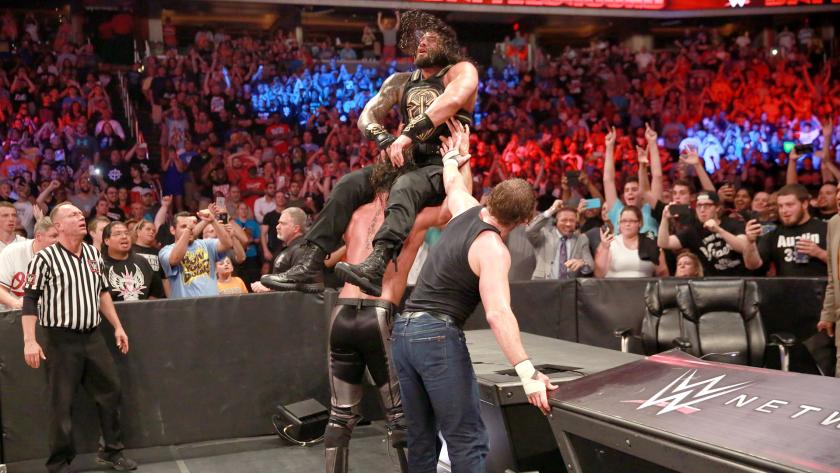 Ambrose and Rollins powerbomb Reigns through a table