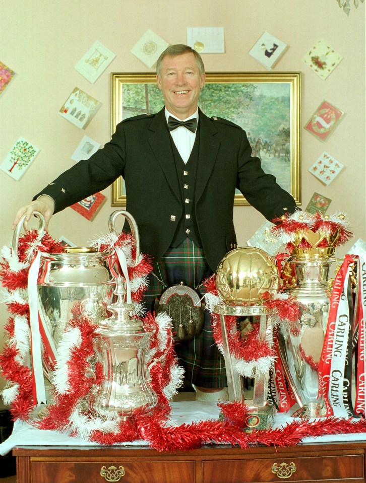 24.12.1999. Picture Bradley Ormesher. Sir Alex Ferguson at home with the treble and world club championship trophy's on Christmas eve.