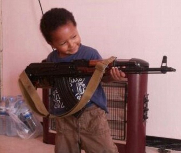  'Jihadi Junior' Isa Dare poses with an AK-47 as a report reveals ISIS are training a new generation of killers