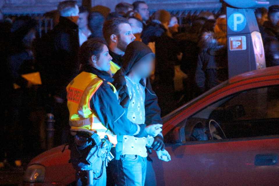  Police arresting a man as people gather in front of the main railway station in Cologne, western Germany after the New Year's Eve attacks on women