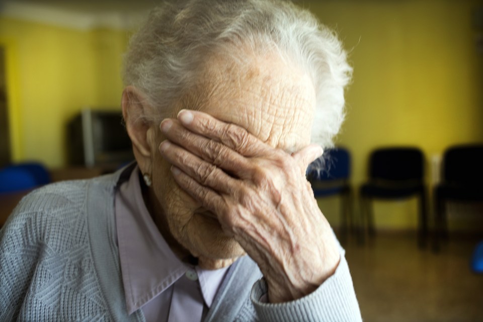 Portrait of centennial woman in elderly people home, hand covering her face