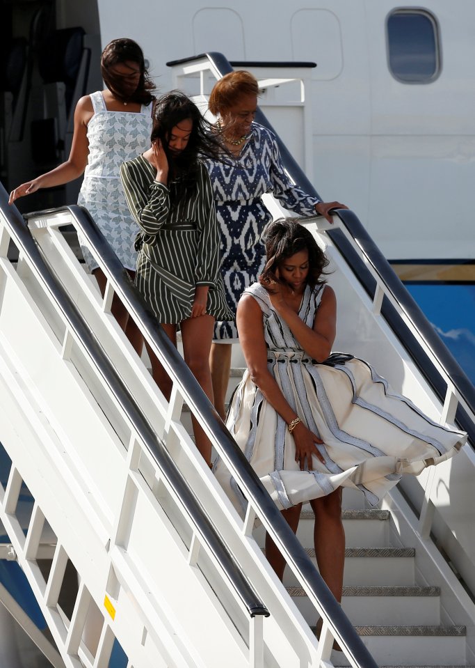 U.S. first lady Michelle Obama tries to control her dress as she steps off her plane with her daughters Sasha and Malia and mother Marian Robinson after arriving at the Torrejon airbase outside Madrid