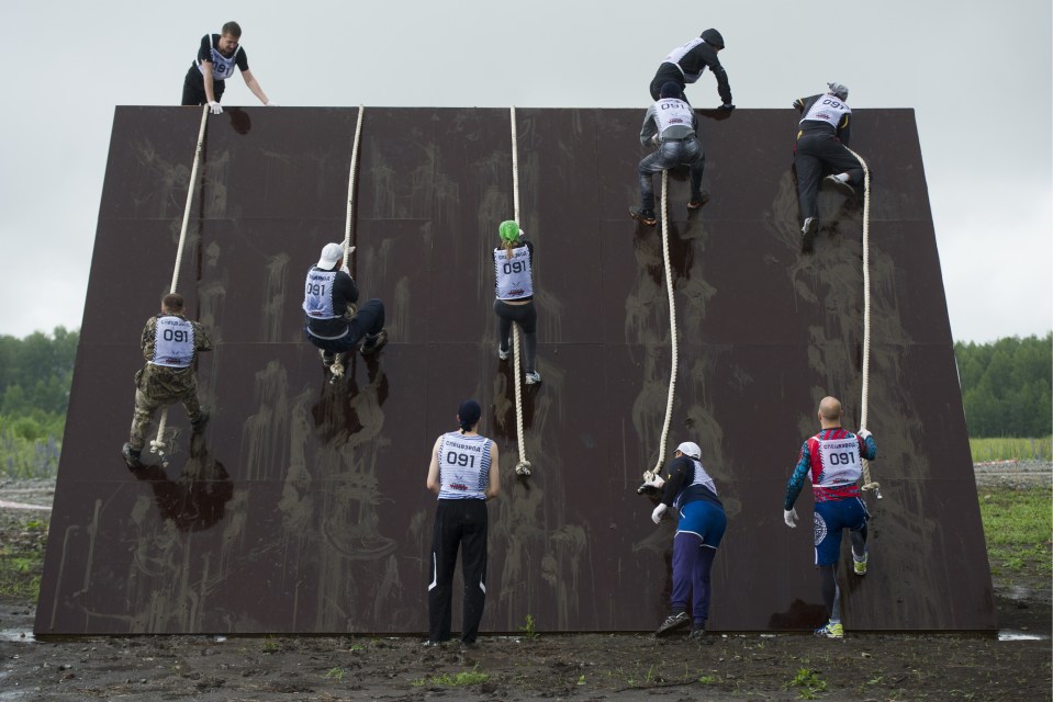 Muddy walls pose challenges to tired and slippery runners, who rely on their upper body strength to scale them