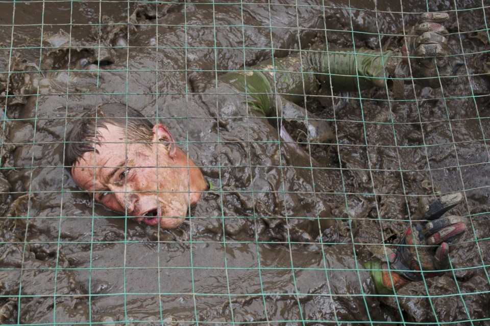 Muddy hell... as if swimming through a lake of mud isn't enough, runners have to climb slippery walls afterwards as well