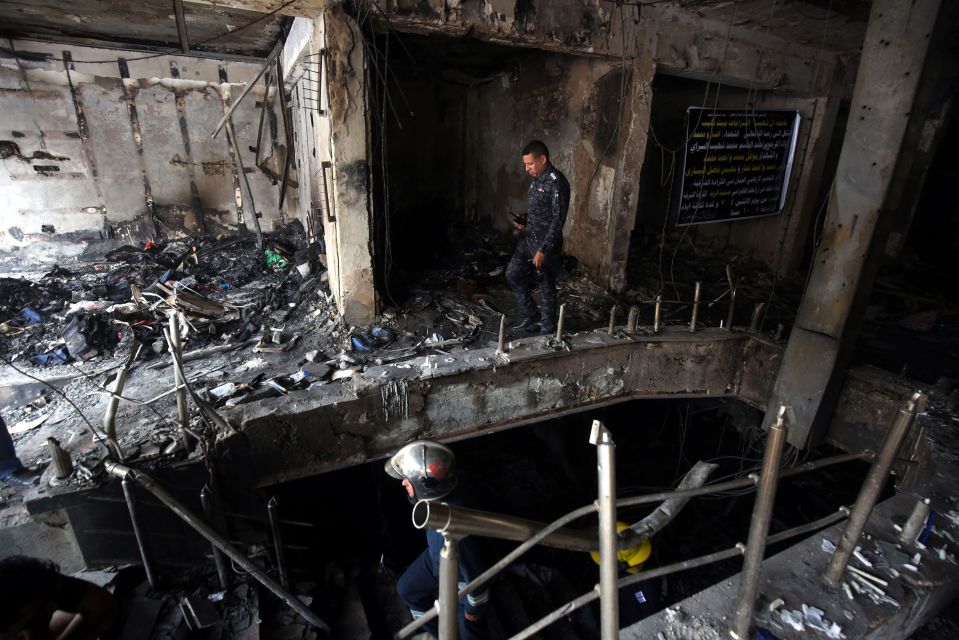  An Iraqi policeman searches for bodies in the building