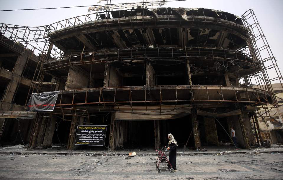  A lone Iraqi woman walks past one of the buildings which was destroyed in the attack