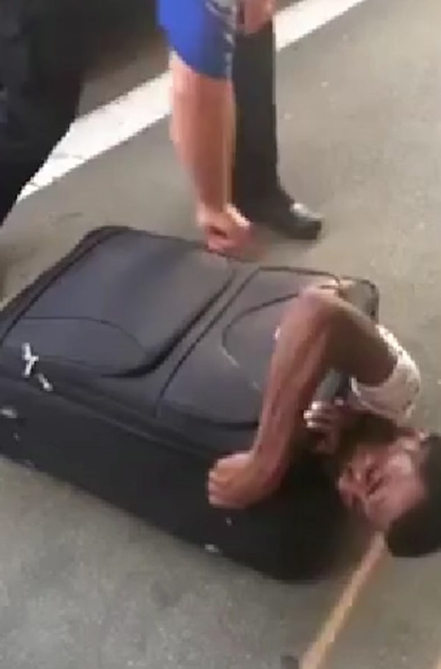  A cop reaches down to help the immigrant who is clearly having some problems unpacking