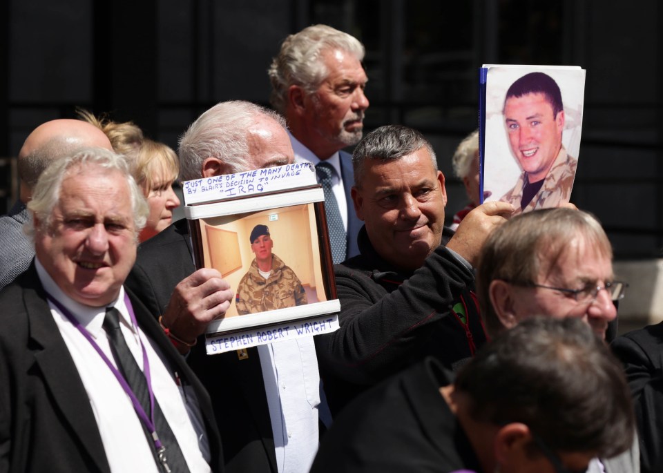  Friends and relatives of those killed in Iraq hold up photos of their loved ones following the release of the Chilcot Report