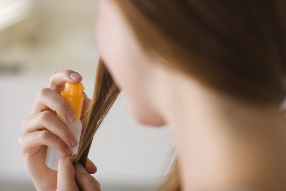 Woman spraying her hair with product